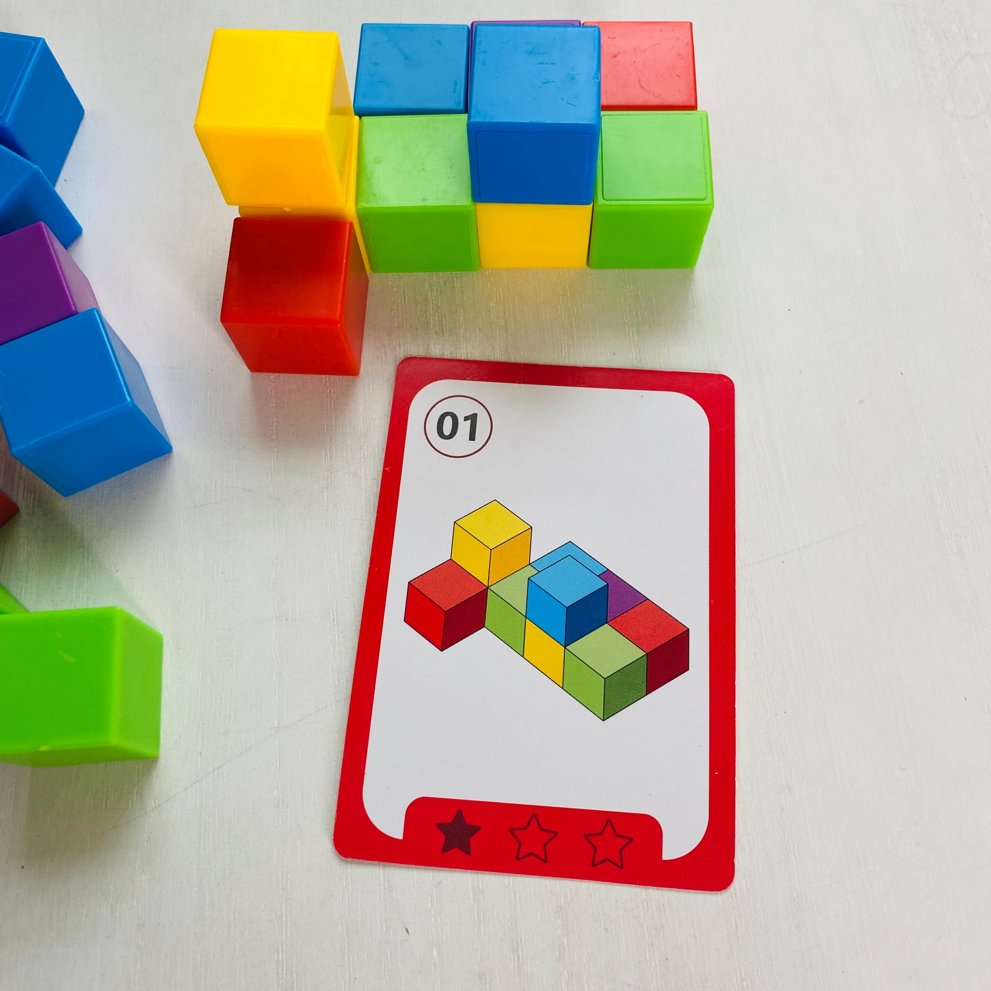 Logic puzzle with colored blocks and 27 double-sided challenge cards. Kids stack the blocks to match the cards.