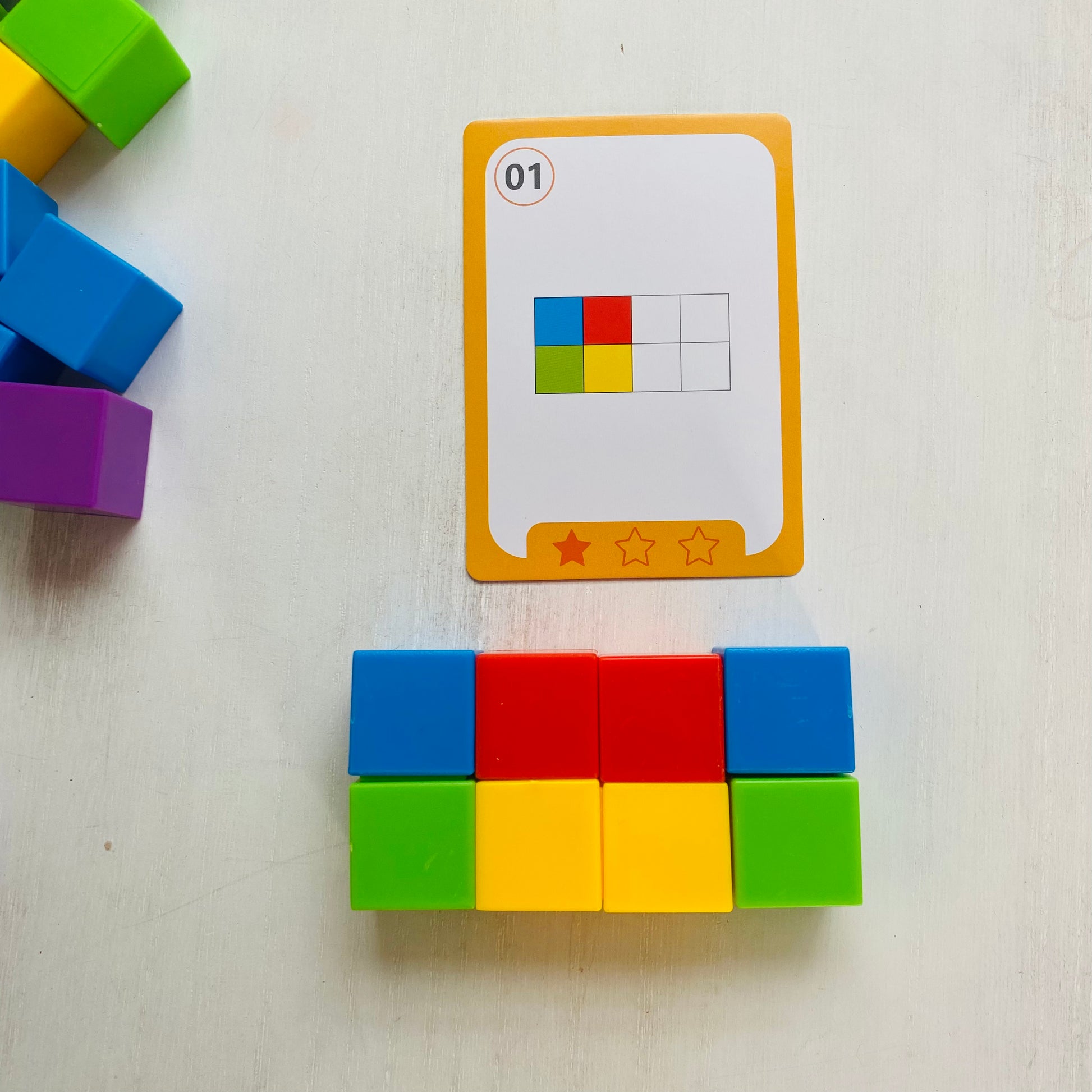 Logic puzzle with colored blocks and 27 double-sided challenge cards. Kids stack the blocks to match the cards.